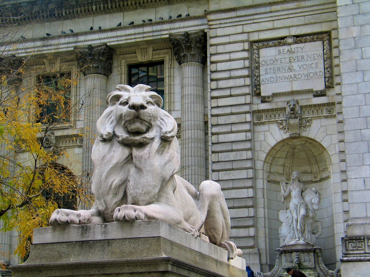 The statuary of the New York Public Library - one of Edward Clark Potter's lions sits in the foreground, with  Frederick MacMonnies' sculptures depicting "Beauty" in the background