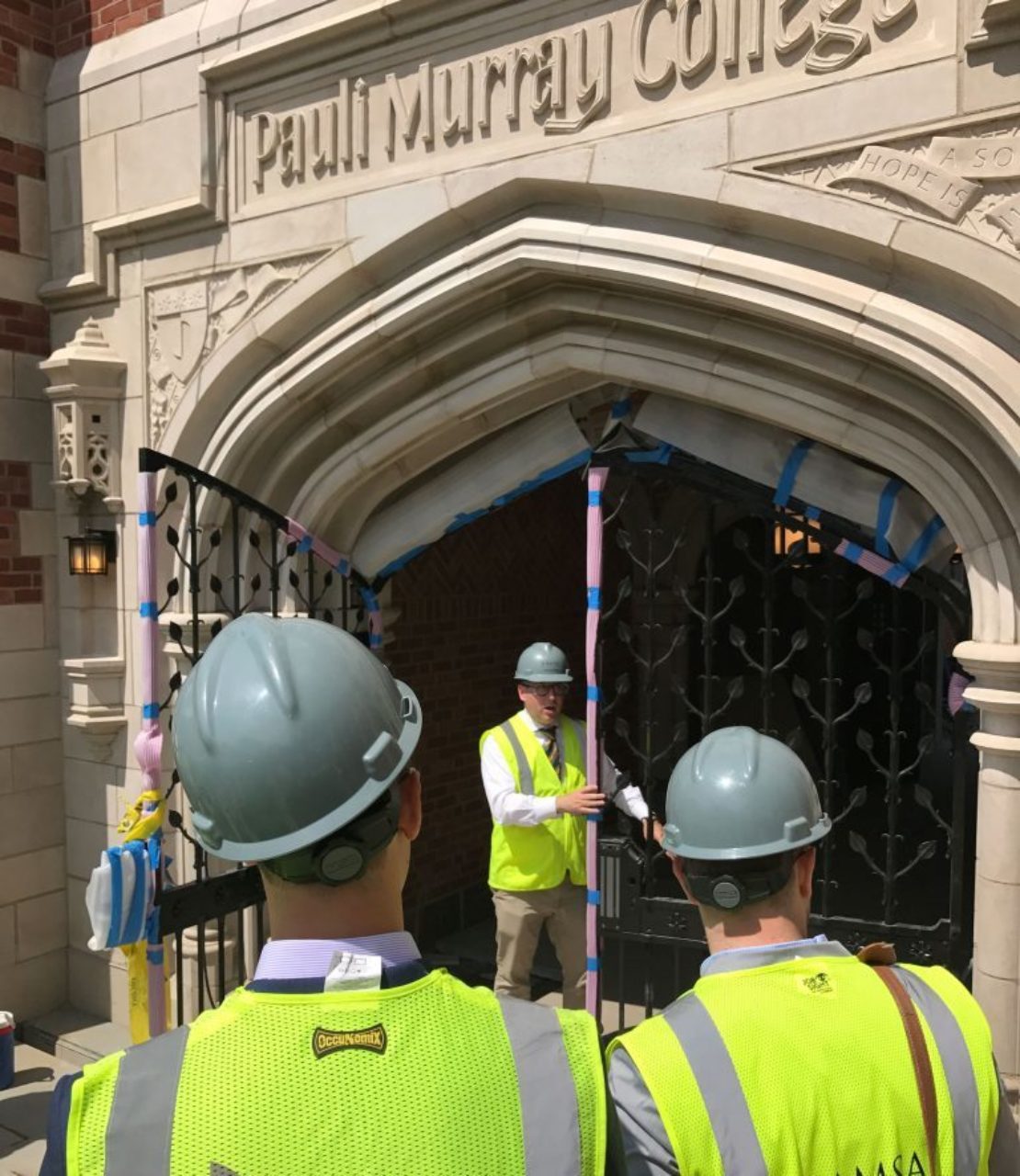 Tour participants inspect the ironwork in the gates at Pauli Murray College